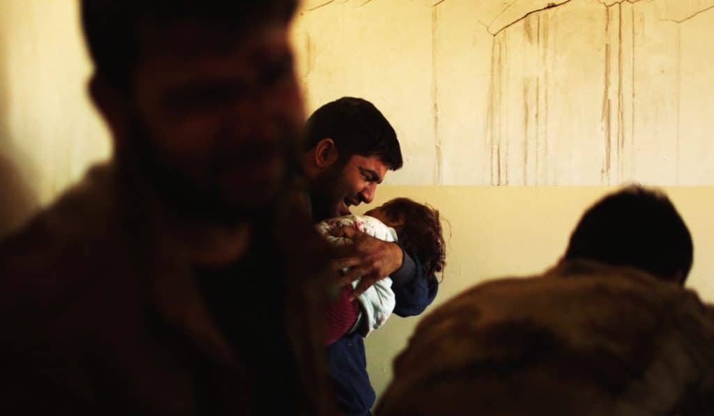 In a field hospital in Mosul, Omar, a father is holding his daughter. She was killed by a bomb. Photo by Mads Kongerskov.